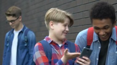 Zalim çok ırklı öğrenciler telefon kaydırma ve alay nerd sınıf arkadaşı online