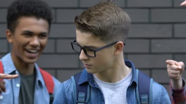 Grupo de adolescentes crueles señalando con los dedos al colegial con gafas, burlándose — Vídeos de Stock