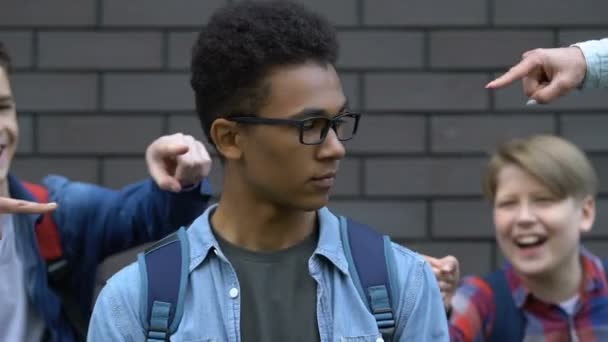 Groep van pestkoppen wijzende vingers bij zwarte student en lachen, discriminatie — Stockvideo