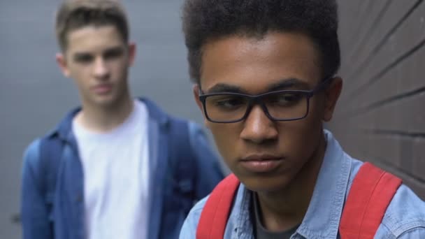 Cruelle caucasien adolescent menaçant et gifler noir guy sur cour de l'école, grossier — Video