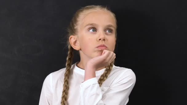 Задумчивая маленькая школьница пожимает плечами, не имея понятия, плохой ученик — стоковое видео