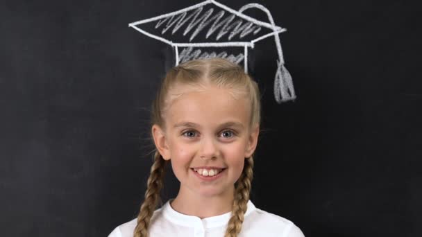 Schoolgirl with square academic cap painted above head smiling at camera — Stock Video