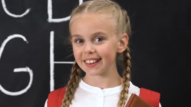 Little Schoolgirl leende på kamera, alfabet skrivet på Blackboard, utbildning — Stockvideo
