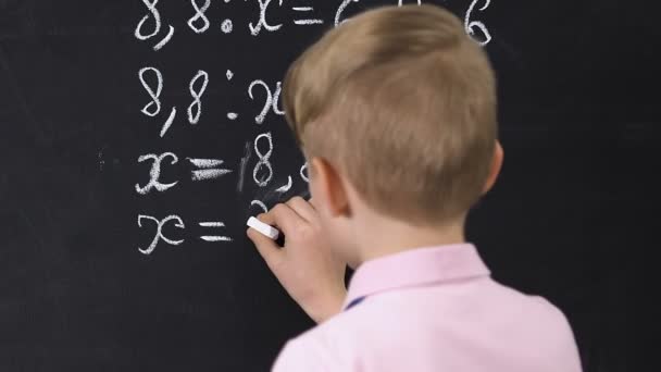 Pequeño niño escribiendo ecuación resultado en pizarra, lecciones de la escuela, vista posterior — Vídeos de Stock