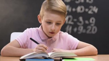 Küçük çocuk okul dersten sonra ev görevi yazma, çözüm altında düşünme, fikir