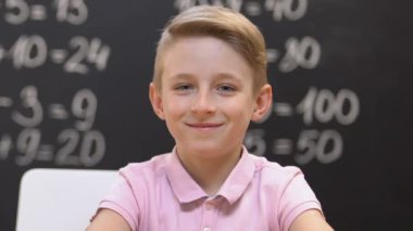 Neşeli öğrenci kameraya bakıyor, tahtadaki matematik denklemleri