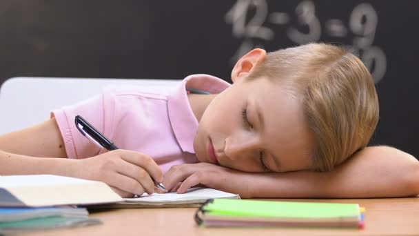 Уставший школьник спит на рабочем столе на уроке, вымотанное образование, переутомление — стоковое видео
