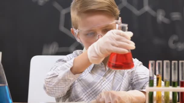 Studente guardando fiaschetta con liquido rosso, scrivendo dati di reazione in copia-libro — Video Stock