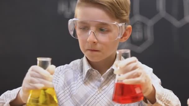 Мужской зрачок смешивает жидкости в колбах на уроке химии, наблюдая реакцию — стоковое видео