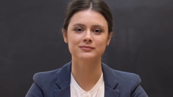 Sonriente profesora mirando a la cámara sobre el fondo de pizarra, clase — Vídeos de Stock