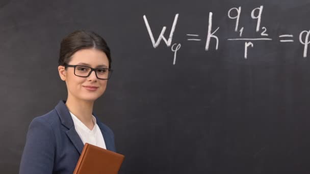 Lachende leraar kijken naar camera, fysieke formule geschreven op Blackboard — Stockvideo