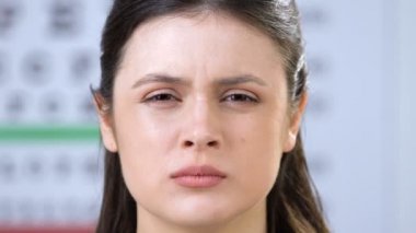 Kısmen kapalı gözlü kadın, hastaların yüzüne phoropter koyan doktor, görme