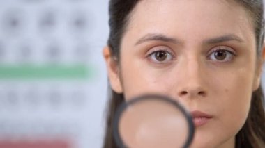 Büyüteçten bakan kadın, konsantre olmaya çalışıyor, görme kontrolü