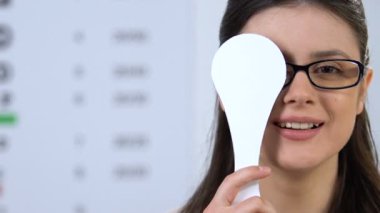 Gözlüklü mutlu kadın bir gözünü kapatıyor, görme kontrol cihazı, sağlık