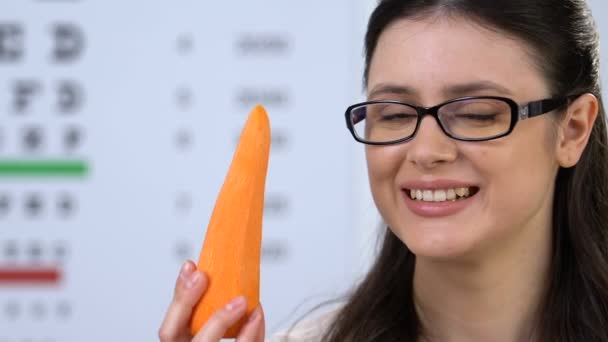 Happy kvinna i glasögon äta morot, färska vitaminer för ögon vård, karoten — Stockvideo