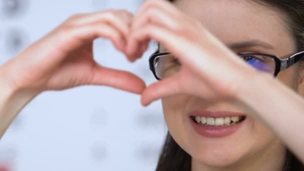 Vrouwelijke in glazen tonen hart teken met handen, Vision gezondheidszorg, kliniek — Stockvideo