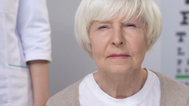 Врач кладет руку на плечо пожилой женщины с плохим зрением, обследование — стоковое видео