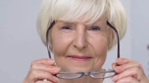 Lächelnde Seniorin setzt Brille auf, ältere Kundin im Optikgeschäft — Stockvideo