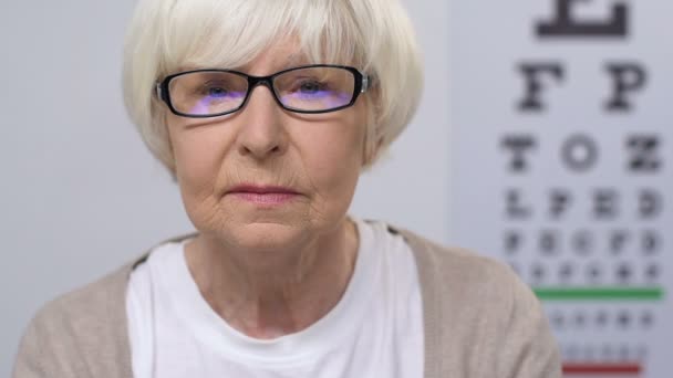 Надмірна старша жінка в окулярах читає газету, проблеми зі зором, хвороби — стокове відео