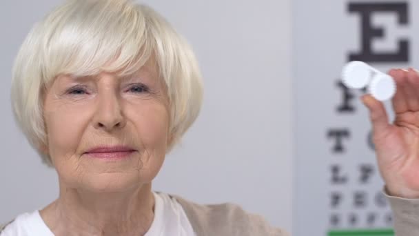 Femme âgée souriante montrant des lentilles cornéennes, recommandation du patient, problèmes de vision — Video