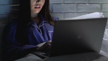 Kadın serbest gece geç saatlerde yatakta dizüstü bilgisayarda yazma, uzaktan erişim, iş