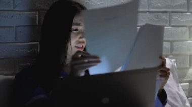 Stresli kadın işçi belgeleri kontrol ve geceleri yatakta dizüstü bilgisayar kullanma