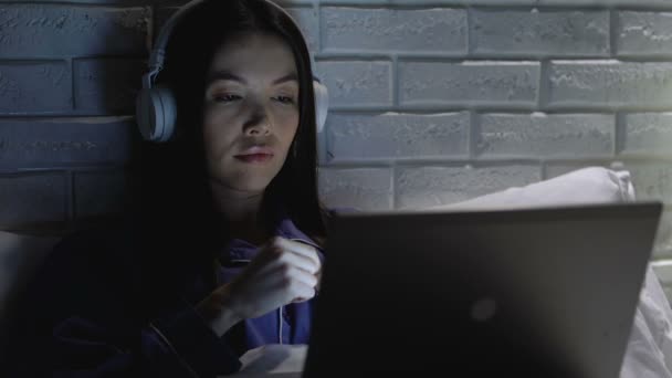 Frau mit Kopfhörer sieht Film auf Laptop und leidet unter Lautstärkestörung — Stockvideo