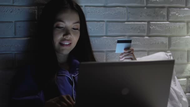 Mulher feliz entrando número de cartão de crédito no laptop à noite, compras on-line — Vídeo de Stock