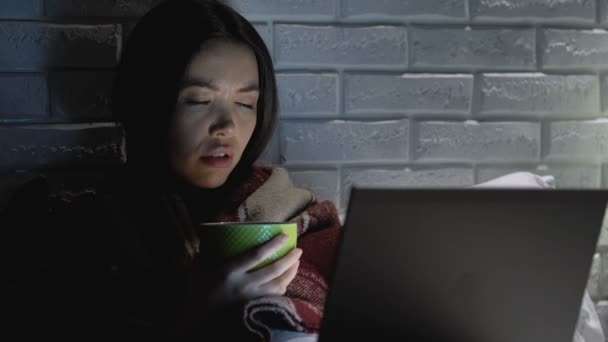 Ziek vrouw met deken drinken thee voor laptop, lijdt aan hoofdpijn — Stockvideo