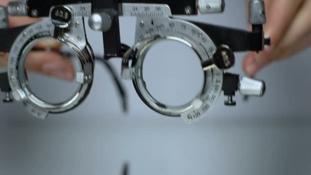 Optik deneme çerçevelerini masaya koyan eller, oftalmik test cihazı yakın çekim — Stok video