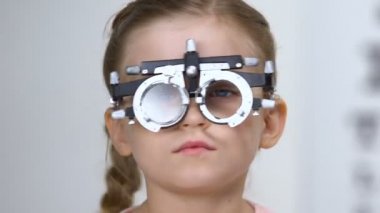 Erkek oftalmolog phoropter giyen küçük kız için gözlük lens seçimi