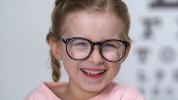 Joyeuse petite fille aux lunettes riant à la caméra, ophtalmologie et santé — Video