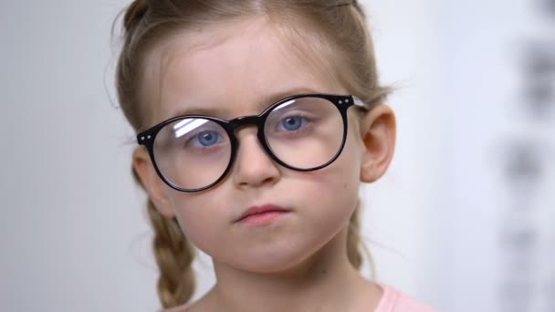 Niño bastante femenino en gafas que cubre la herramienta de examen ocular, prueba médica — Vídeo de stock
