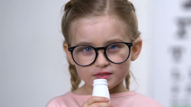 Entzückende kaukasische Mädchen in Brillen Milchflasche trinken, vitaminisiertes Getränk — Stockvideo