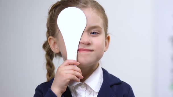 Pequeña colegiala con dispositivo de prueba de visión sonriendo en la cámara, examen médico — Vídeo de stock