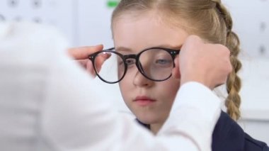 Gözlük küçük kız öğrenci ayna görünüm, optik ile mutsuz bakarak