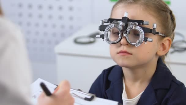 Enfant dans un cadre d'essai optique médecin prescrivant des lunettes, ophtalmologie — Video