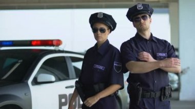 Devriye arabasına karşı duran üniforma lı ve güneş gözlükli kendinden emin polis takım arkadaşları