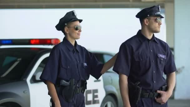 Дружні поліцейські в уніформі і окулярах посміхаються до камери, закону і порядку — стокове відео