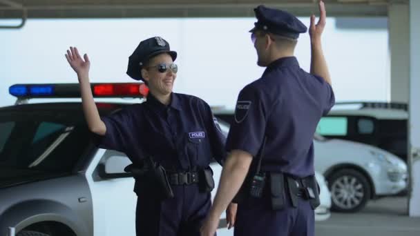 Mannelijke en vrouwelijke politieagenten geven hoge vijf communicatie op parkeerplaats — Stockvideo