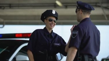 Arkadaşıyla konuşan ve devriye arabasının yanında gülen polis memuru, mola verdi