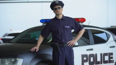 Servis kapağı ve güneş gözlüğü cesur polis devriye arabası yakınında kamera için poz