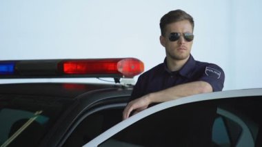 Polis arabasının kapısının yanında duran güneş gözlüğü izleme yol ciddi devriye