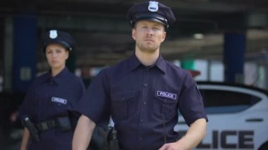 Devriye arabasının yanında üniformalı kendine güvenen erkek ve kadın polis memurları