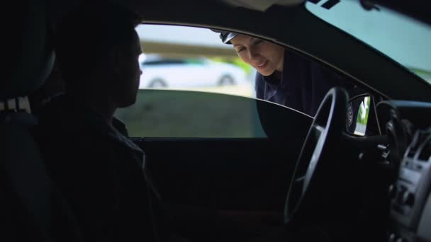 Přátelská policejní žena kontroluje řidičský průkaz člověka v autě, prohlídka silničního provozu — Stock video