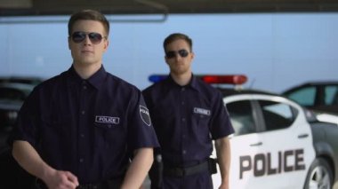 Güneş gözlüğü takan erkek memurlar polis aracına el leriyle geçti