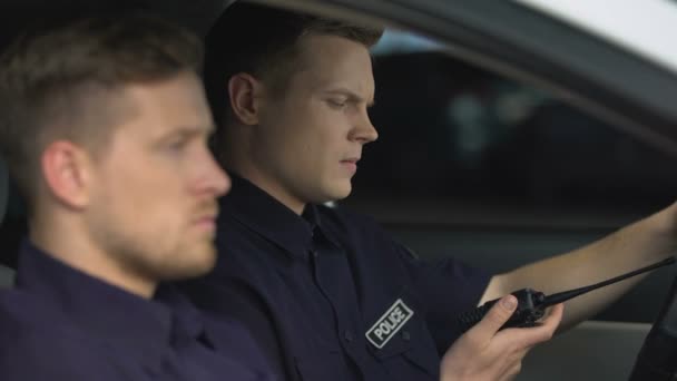 Un policier parle sur une radio portable dans une voiture de patrouille, appelant au renfort — Video