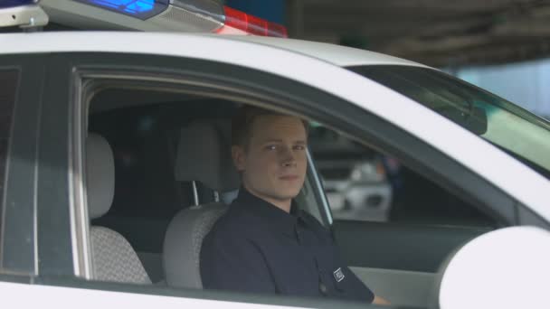 Lachende politieagent kijkend naar camera van politie auto, belangrijk beroep — Stockvideo