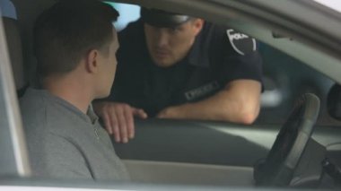 Genç erkek sürücü polis memuruna belge veriyor, trafik kontrolü, kurallar