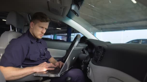 Oficial de policía masculino trabajando en el ordenador portátil en el coche, llenando los datos en el informe del crimen — Vídeo de stock